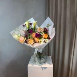 Bouquet of peach and purple flowers in a clear glass vase