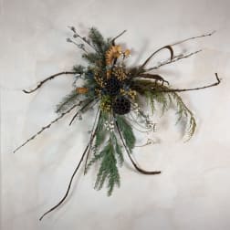 Wall-mounted arrangement with pine branches, twigs, and seed pods