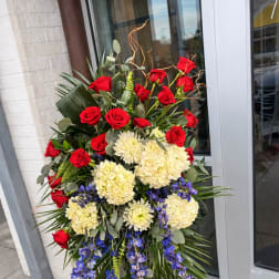 Standing floral spray with red roses, cream blooms, and blue orchids