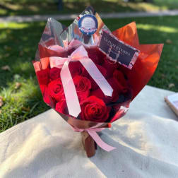 Red rose bouquet wrapped in shiny red and silver paper with a pink ribbon