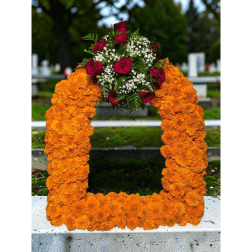 Orange marigold funeral wreath with red roses and white filler flowers