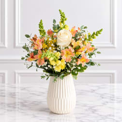Bouquet of peach and yellow flowers in a white vase