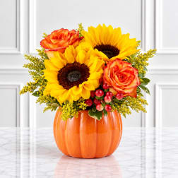Sunflowers and orange roses arranged in a pumpkin vase