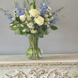 White roses and blue delphinium in a clear glass vase