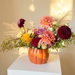 Mixed bouquet in an orange vase with pink, purple, and yellow flowers