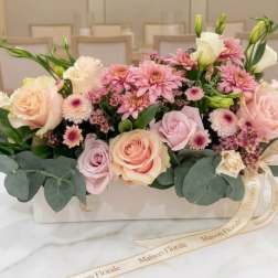 Pink and cream flower arrangement in a white box with ribbon