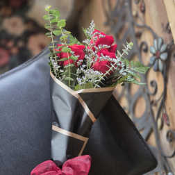 Bouquet of red roses wrapped in black paper with a pink bow