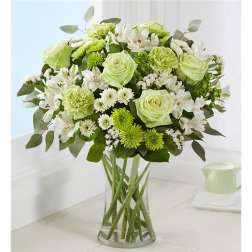 Green and white bouquet of roses, carnations, and daisies in a clear glass vase