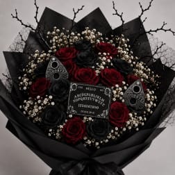 Bouquet of red and black roses with small white filler flowers in black wrap