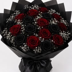 Bouquet of red and black roses wrapped in black paper with baby's breath