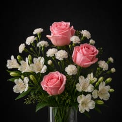 Pink roses and white flowers arranged in a clear glass vase