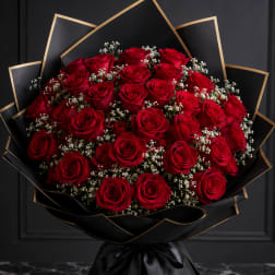 Bouquet of red roses wrapped in black paper with gold trim