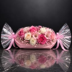 Pink and cream rose arrangement wrapped in pink paper with clear cellophane bows