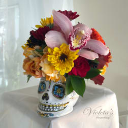 Mixed bouquet in a decorated skull vase with pink lilies and bright daisies