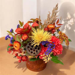 Colorful autumn floral arrangement in a pumpkin-decorated vase