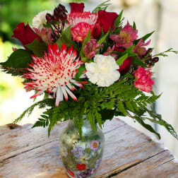 Bouquet of red, pink, and white flowers in a decorated glass vase