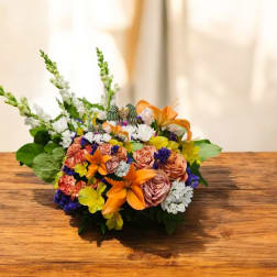 Mixed bouquet with orange lilies, peach roses, and white blooms on a wooden table