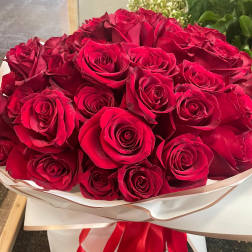 Bouquet of red roses wrapped in white paper with a red ribbon