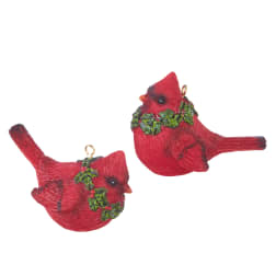 Two red cardinal ornaments with holly wreath accents on a white background