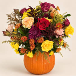Mixed autumn bouquet in a pumpkin vase with roses and mums