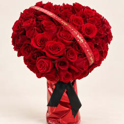 Large bouquet of red roses with a decorative ribbon in a red wrapped vase
