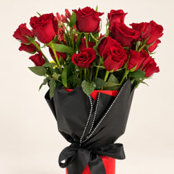 Bouquet of red roses wrapped in black paper with a ribbon