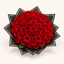 Large bouquet of red roses wrapped in black paper with gold trim