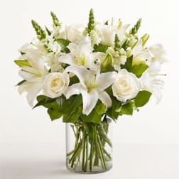 White lilies and roses arranged in a clear glass vase