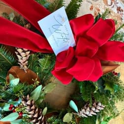 Holiday wreath with a large red bow and pinecones