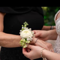 White floral wrist corsage being fastened on a bride's wrist
