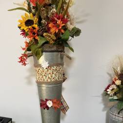 Tall autumn floral arrangement in a metal vase with sunflowers and orange blooms