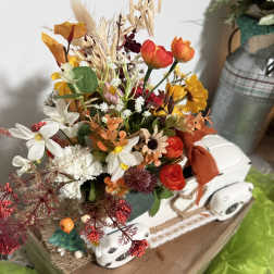 Mixed bouquet with orange, white, and red flowers in a white container