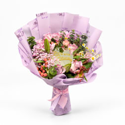 Pink mixed bouquet wrapped in lavender paper with a ribbon