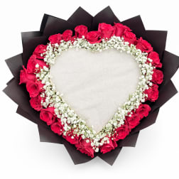 Heart-shaped bouquet of pink roses and white baby's breath on black wrap