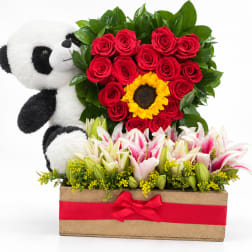 Panda plush beside red roses and lilies in a wooden box with a red ribbon