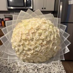 Large round bouquet of cream roses wrapped in translucent paper