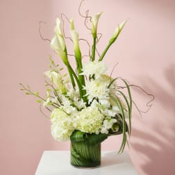White floral arrangement with calla lilies and chrysanthemums in a glass vase