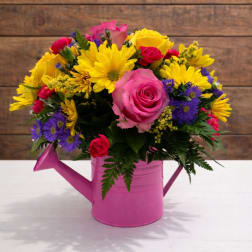 Bright mixed bouquet in a pink watering can vase