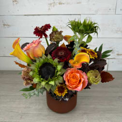 Mixed bouquet with sunflowers, roses, calla lilies, and chrysanthemums in a brown vase