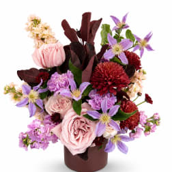 Pink roses and purple flowers arranged in a brown vase