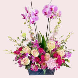 Pink and purple floral arrangement in a dark rectangular container