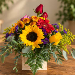 Mixed bouquet with sunflowers, roses, and gerbera daisies in a wooden box