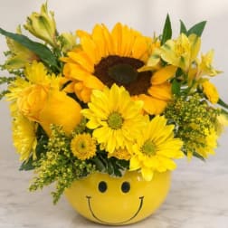 Yellow flower arrangement in a smiley-face container