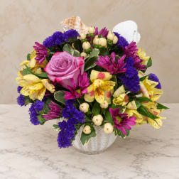 Mixed bouquet of purple, pink, and yellow flowers in a white vase