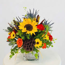 Bright mixed bouquet with sunflowers and orange roses in a glass vase