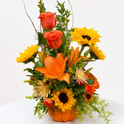 Orange and yellow floral arrangement in a pumpkin-shaped container