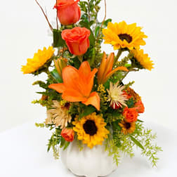 Orange roses and lilies with sunflowers in a white vase
