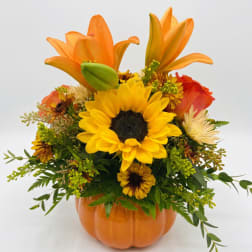 Orange and yellow floral arrangement in a pumpkin-shaped vase