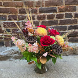 Mixed bouquet of red roses and pale pink flowers in a glass vase