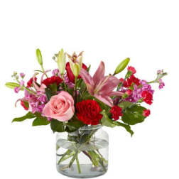 Mixed bouquet of pink and red flowers in a clear glass vase